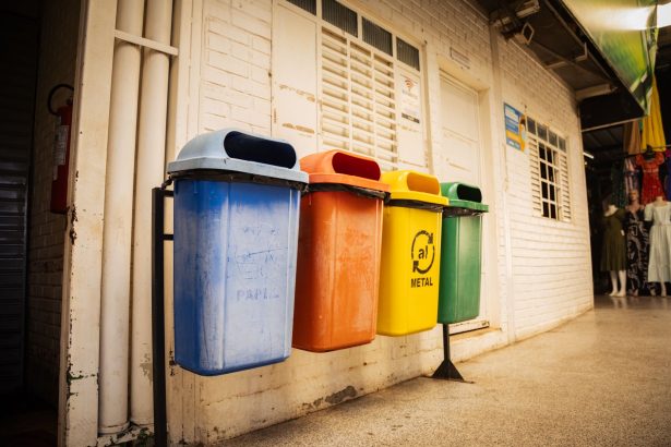 Quatro contentores para separação de papel, plástico, metal e vidro num espaço interior.