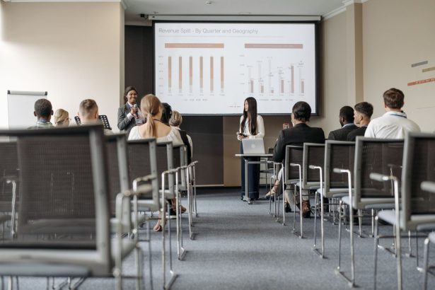 Participantes de uma conferência acompanham uma apresentação com gráficos sobre dados econômicos.
