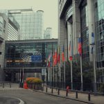 Edifício do Parlamento Europeu em Bruxelas com bandeiras da União Europeia.