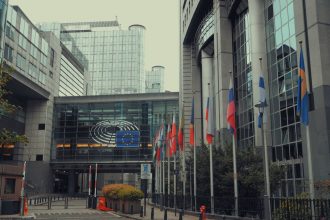 Edifício do Parlamento Europeu em Bruxelas com bandeiras da União Europeia.