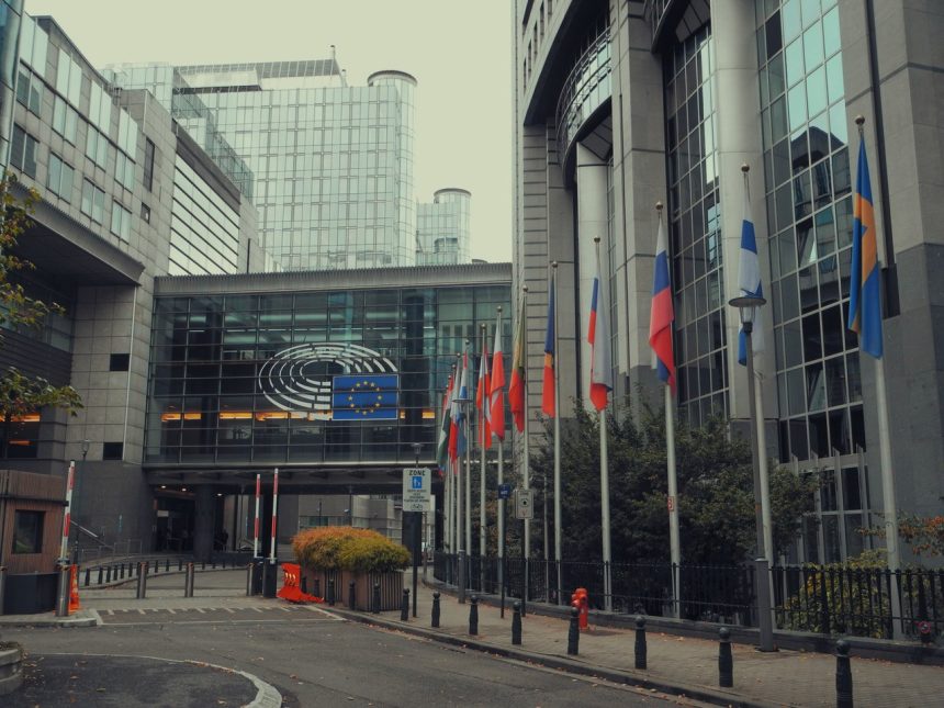 Edifício do Parlamento Europeu em Bruxelas com bandeiras da União Europeia.